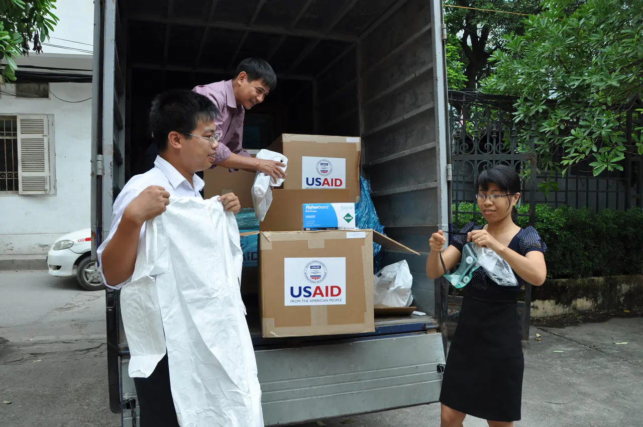 Nguyen Dug Hanh of Vietnam's Department of Animal Health (on truck),transport supervisor Doan Phu Huyen (left) and Nguyen thi Thanh Diep inspect a shipment of 1,700 personal protection kits -- suits, masks, gloves, goggles and related items -- in September 2011 before they are shipped to Can Tho, Ha Nam, Hung Yen, Kieng Giang, and Quang Tri provinces to help veterinary officials and animal health works battle disease outbreaks in the country. Photo: Richard Nyberg, @USAIDVietnam
