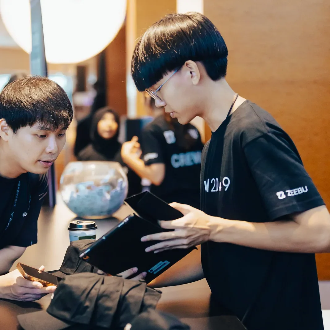 Staff walking an attendee through a tablet at an expo desk, TOKEN2049 Singapore 2024 · editorial context
