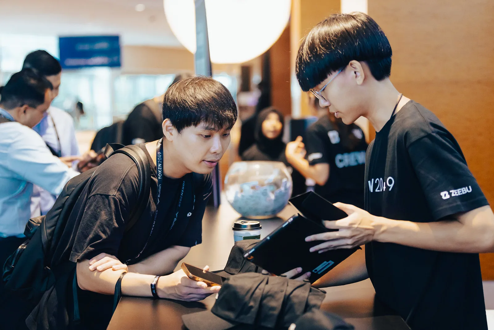 Event staff and attendees at an expo desk, TOKEN2049 Singapore 2024