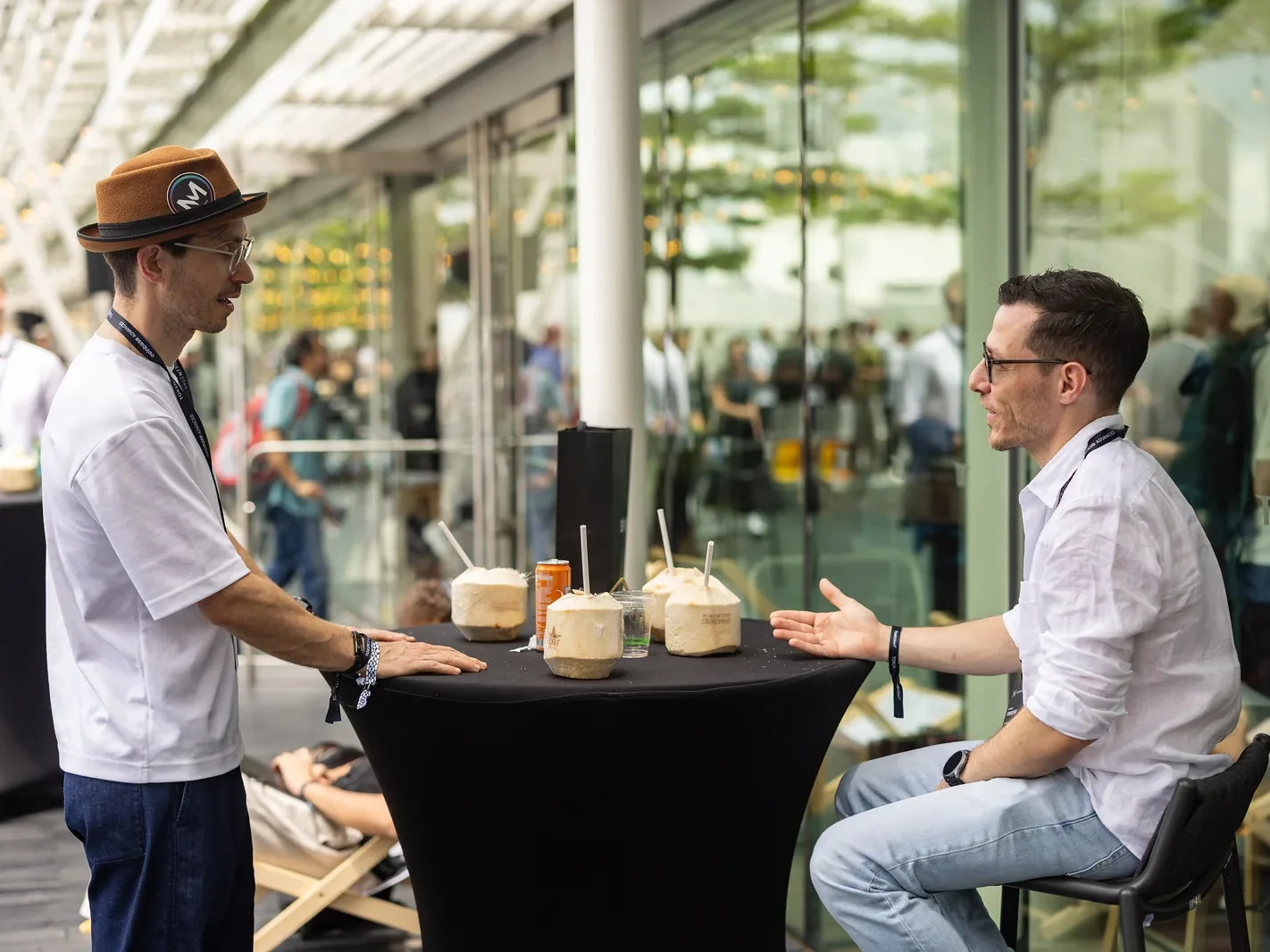 Two attendees in conversation at a standing table, TOKEN2049 Singapore 2025 · editorial context