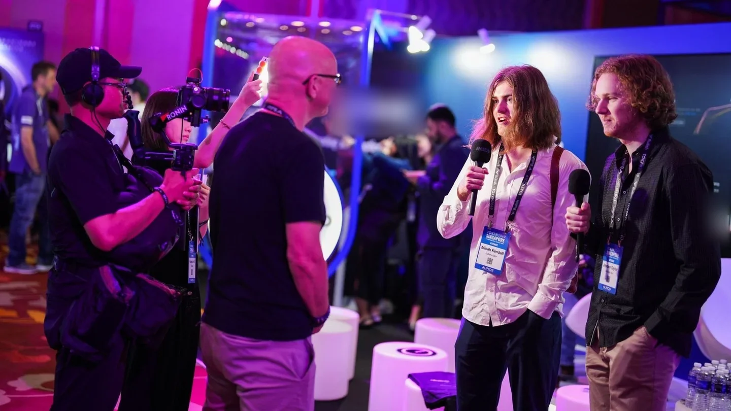 Camera crew recording an interview at an expo booth, TOKEN2049 Singapore 2024 · editorial context